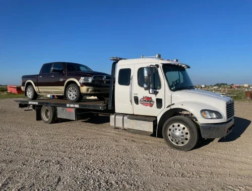 Medium-duty towing service moving a box truck with professional tow equipment.